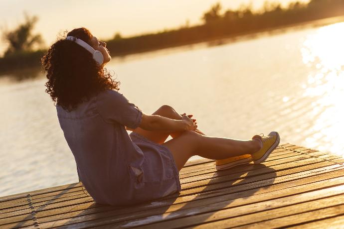 Femme qui écoute de la musique au soleil le long d'un fleuve
