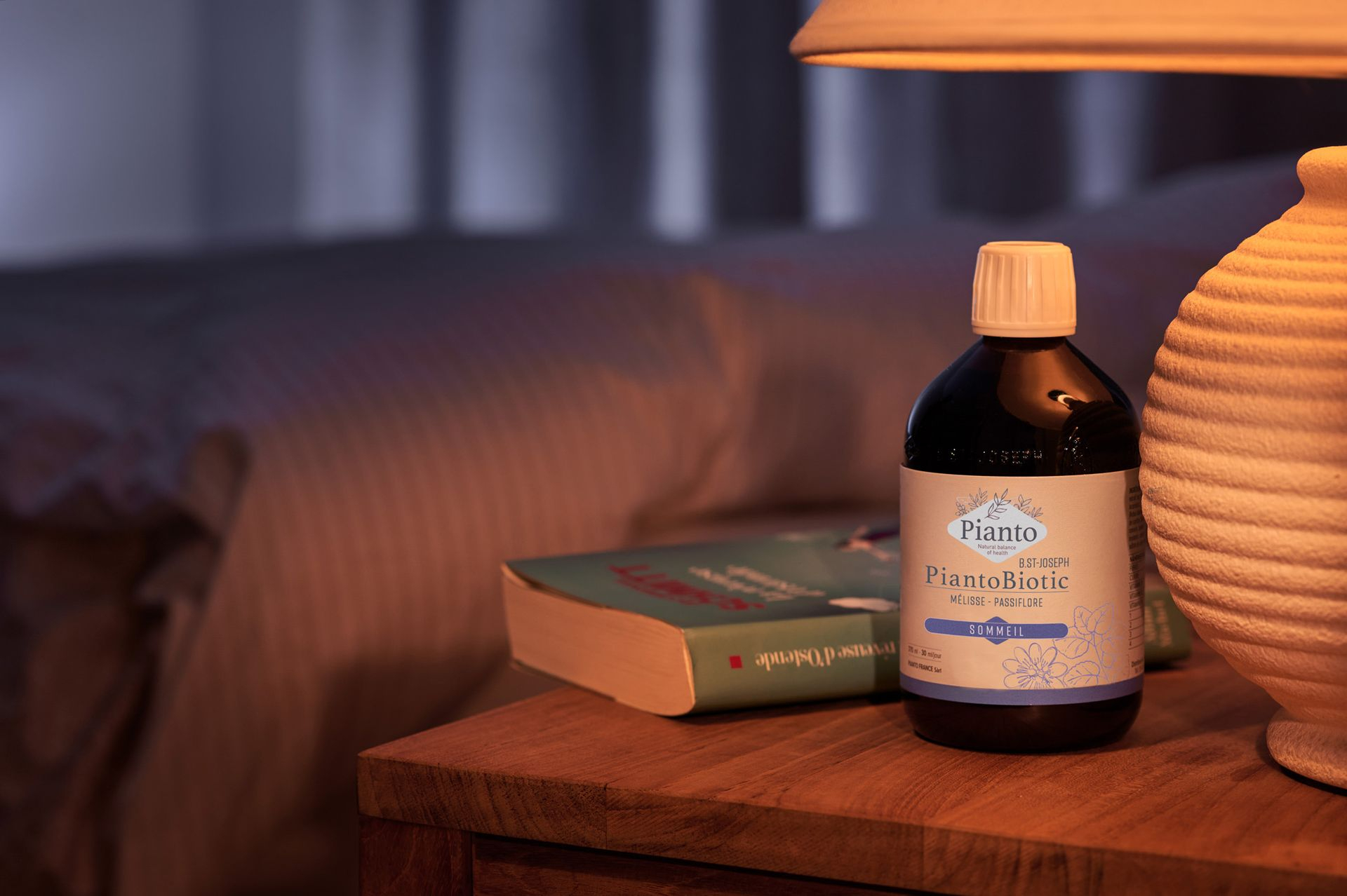 Bouteille de PiantoBiotic (Ex B.St-Joseph) Sommeil sur une table de chevet avec une lampe et un livre