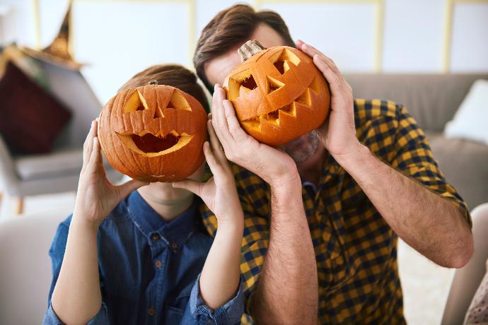 Un père et son fils avec une citrouille devant la tête