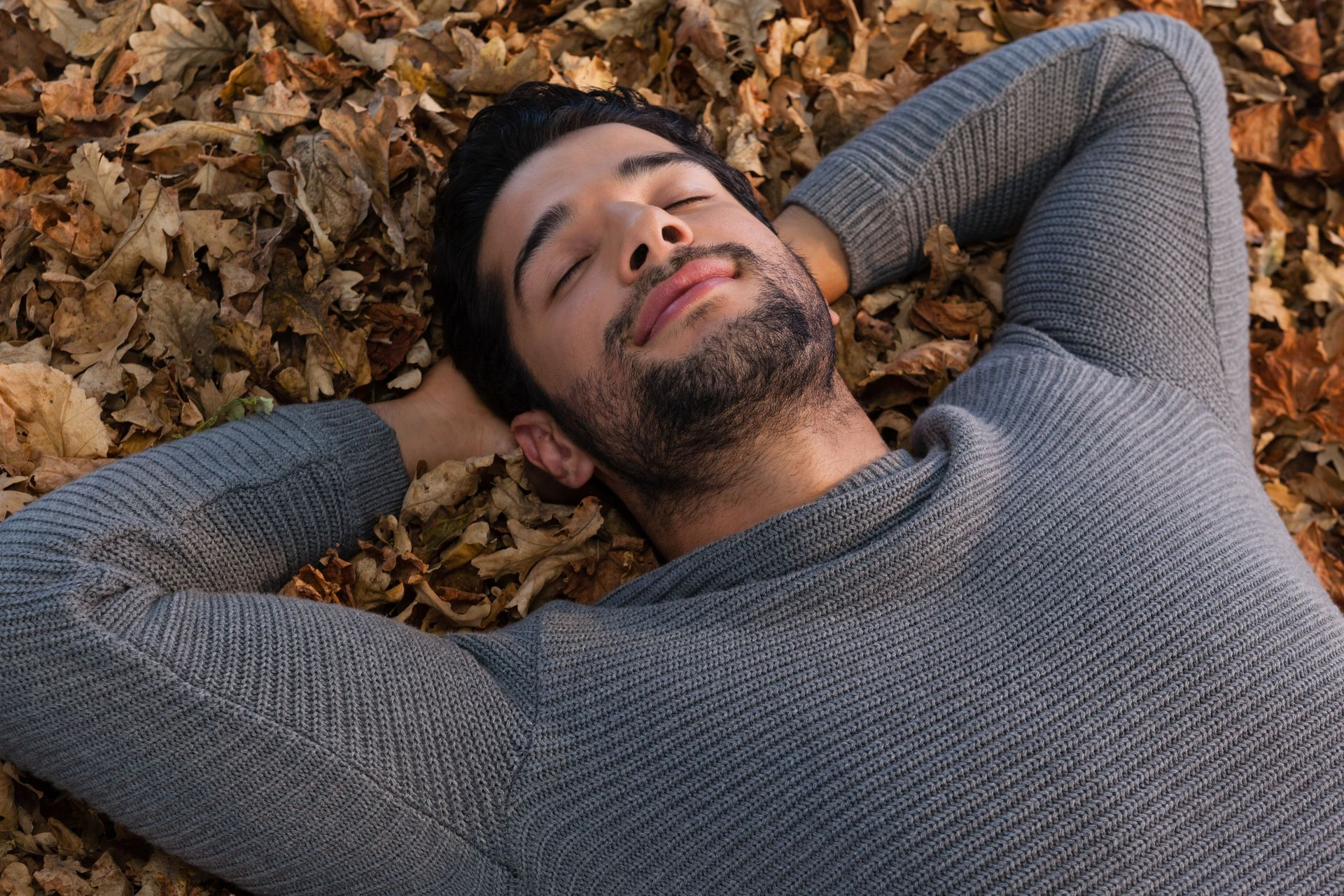 Jeune homme coucher, les yeux fermés, dans des feuilles d'automne