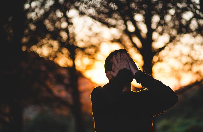 Homme stressé avec les mains sur le visage.