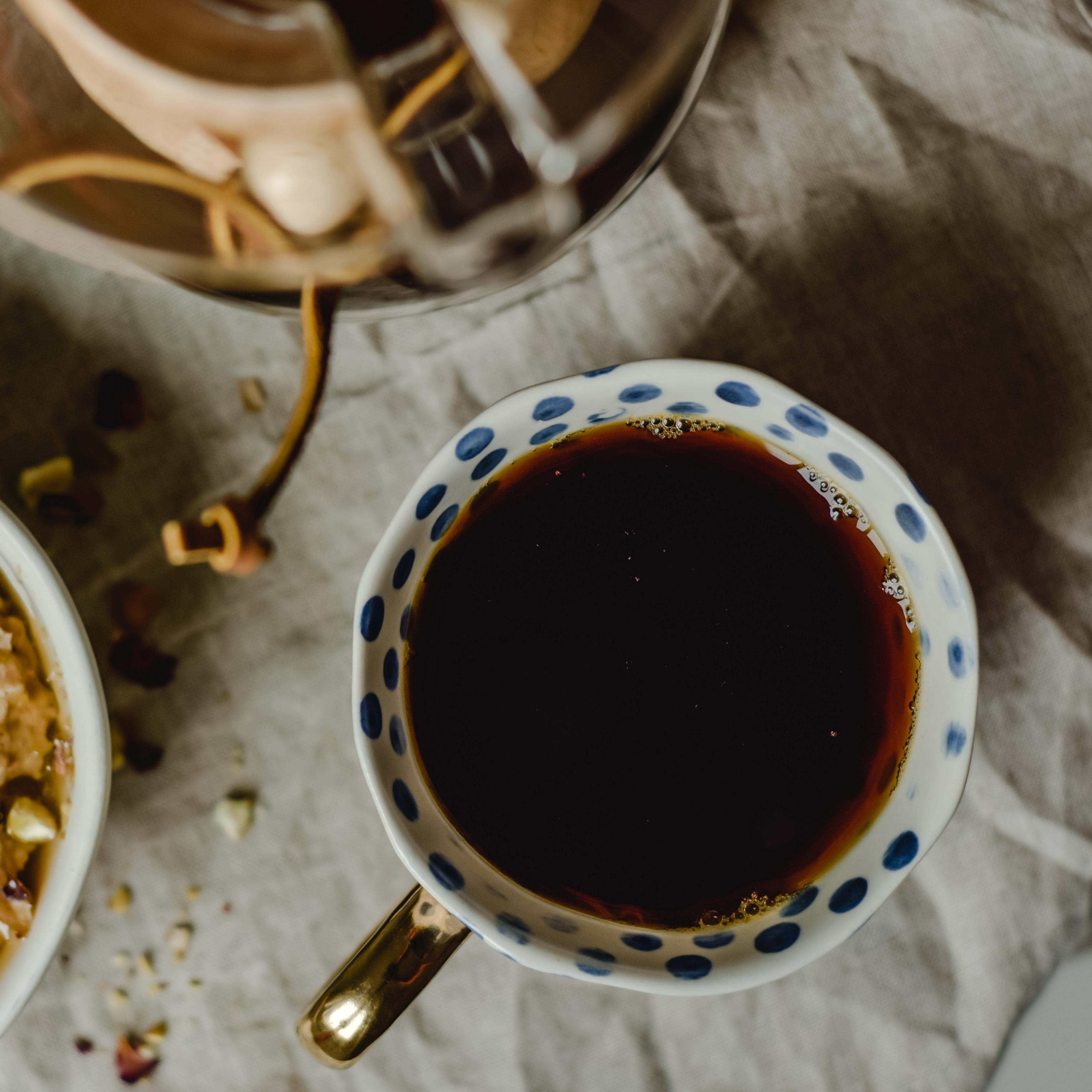 Tasse blanche avec des petits ronds bleus remplie de thé 