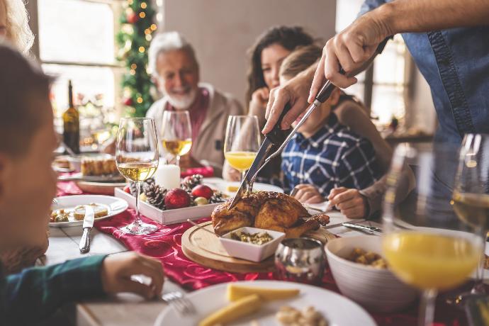 Famille heureuse autour d'une table célébrant noël avec une dinde au milieu de la table 