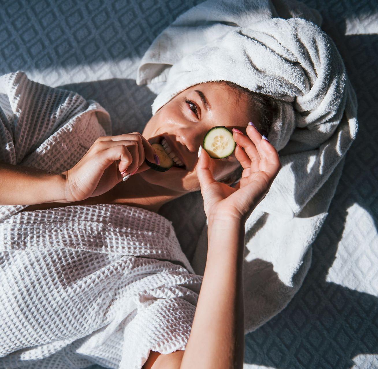 Jeune femme souriante avec une rondelle de concombre sur un oeil 