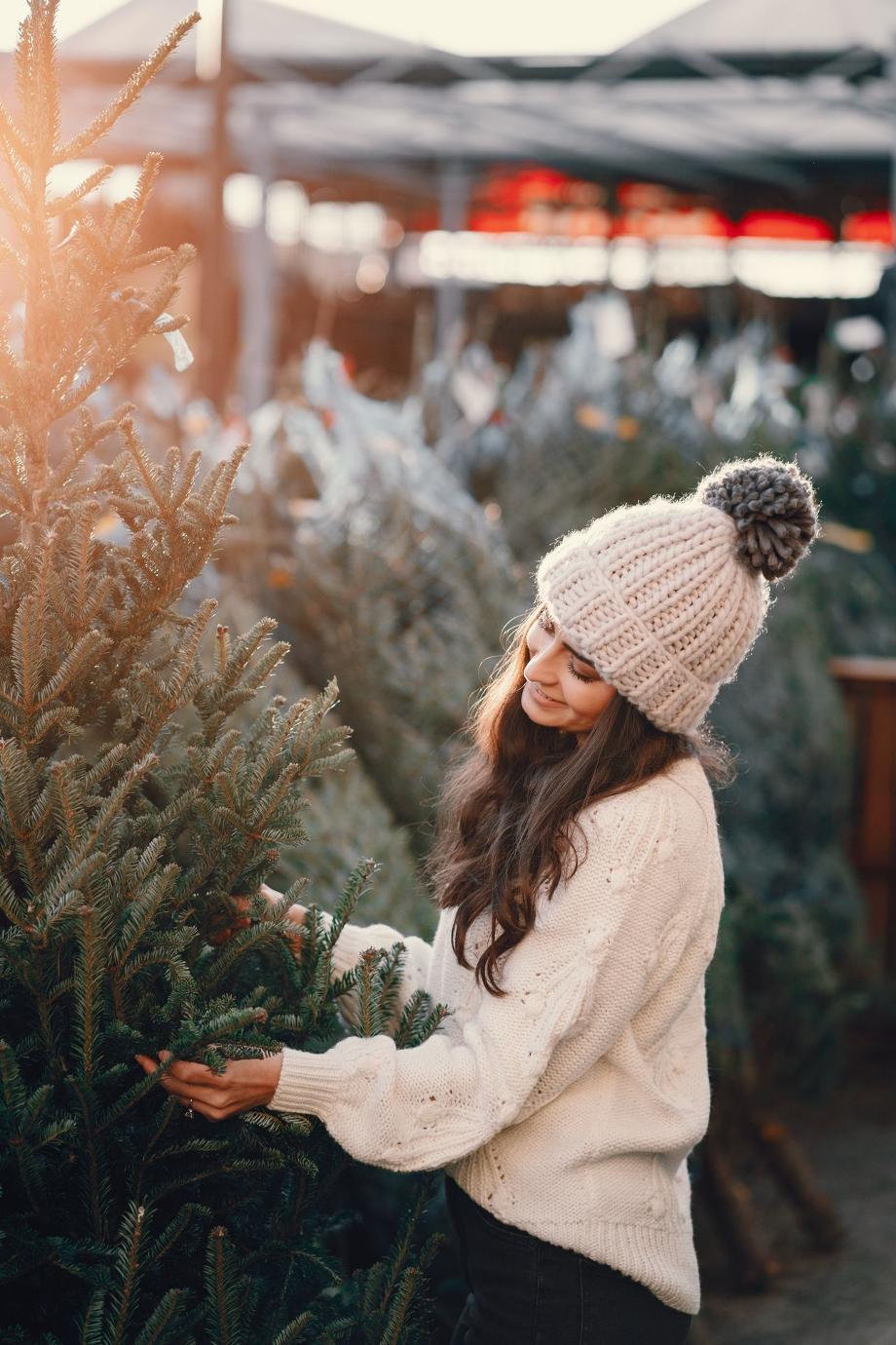 Jeune femme souriante  avec un bonnet occupée à regarder un sapin