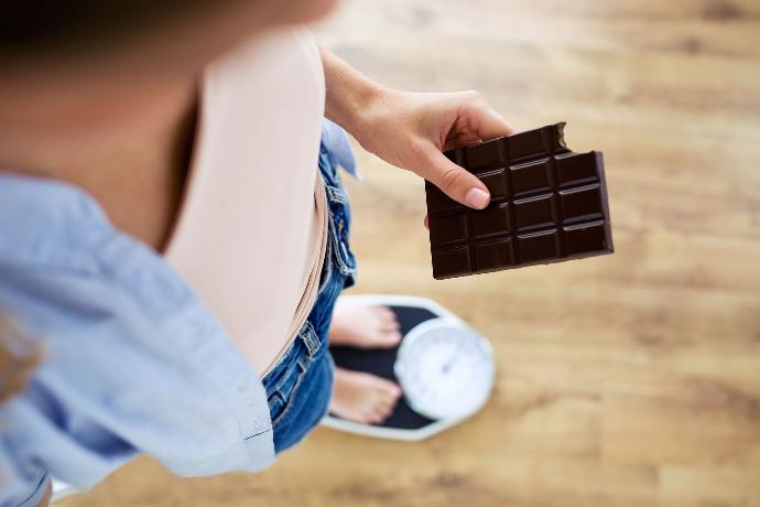 Femme sur une balance avec une tablette de chocolat 